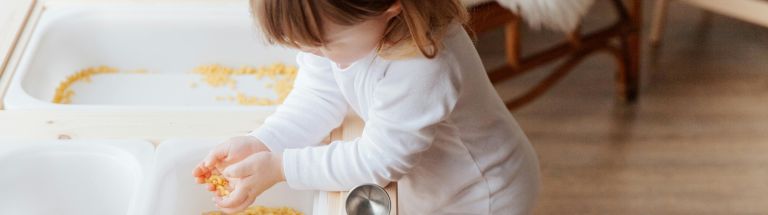 Young girl playing with pasta shapes