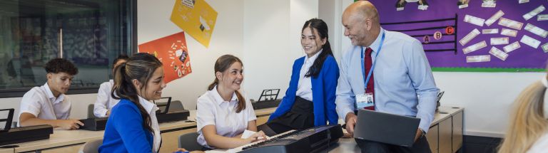 Male teacher talking with three teenage female students