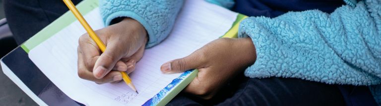 Child writing on paper with pencil