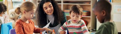 Female educator smiling as children colour and draw