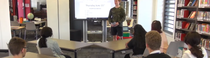 Student stands in front of presentation screen in front of class