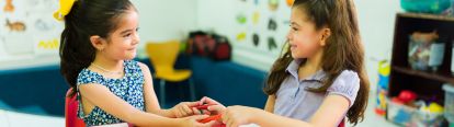 Two young girls sharing pencils