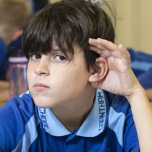 Boy holding his ear to listen